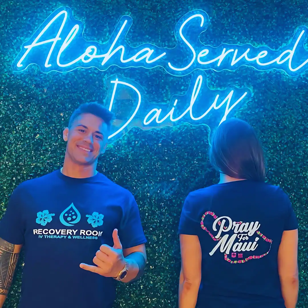 Recovery Room team members in front of the Aloha Served Daily neon sign
